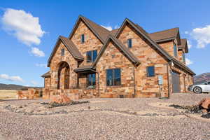 View of front of property featuring stone siding, a mountain view, a garage, and a shingled roof