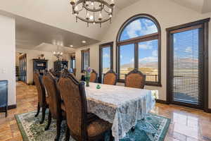 Dining room featuring suspended lighting, stone tile floors, a mountain view, and a high ceiling