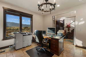 Office area featuring stone tile flooring and a chandelier