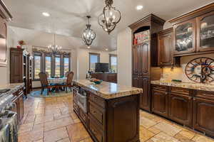 Kitchen with glass insert cabinets, suspended lighting, a textured ceiling, stainless steel appliances, and dark wood finish cabinetry