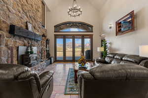 Living area with stone tile floors, vaulted ceiling, a mountain view, a wood stove, and hanging lights