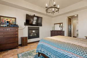 Bedroom with stone tile flooring, a glass covered fireplace, and hanging lights