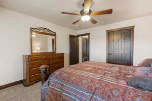 Bedroom featuring light colored carpet, a ceiling fan, a closet, and a textured ceiling