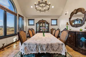 Dining room with stone tile flooring, vaulted ceiling, hanging lights, and a mountain view
