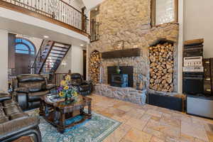 Living area featuring a high ceiling, a wood stove, and stone tile flooring