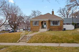 Bungalow featuring brick siding, a chimney, and roof with shingles