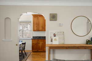 Kitchen featuring wood finish cabinetry, light wood finished floors, and dark stone counters