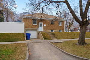 View of front of property featuring brick siding, a front yard, concrete driveway, and a garage