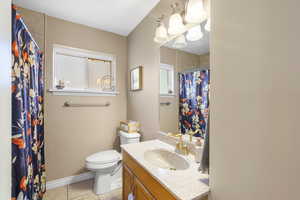 Full bath with vanity, light tile patterned flooring, and curtained shower