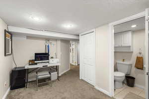 Office area featuring a textured ceiling and light colored carpet