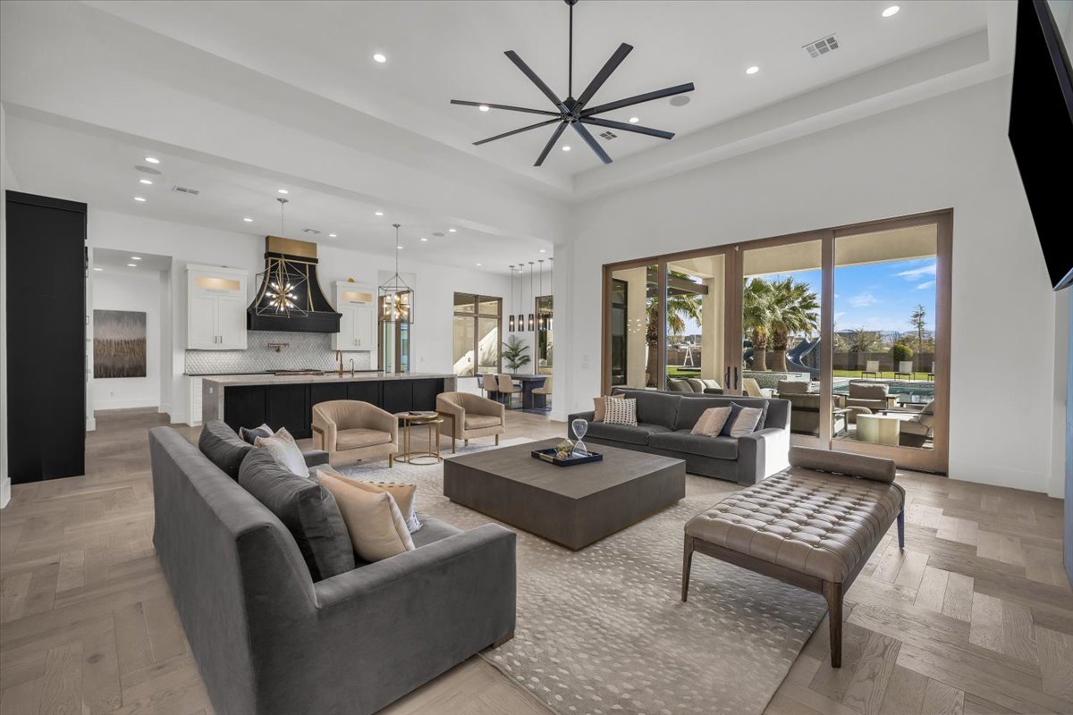 Living area featuring parquet floors, ceiling fan, recessed lighting, and a high ceiling