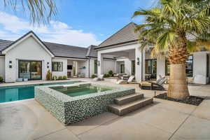 Rear view of property with a patio area, stucco siding, a tile roof, and a pool with connected hot tub