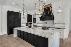 Kitchen featuring dark stone countertops, parquet flooring, a large island, backsplash, and two tone cabinetry
