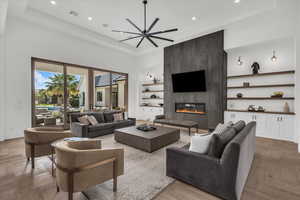Living room with parquet floors, built in shelves, ceiling fan, a fireplace, and recessed lighting