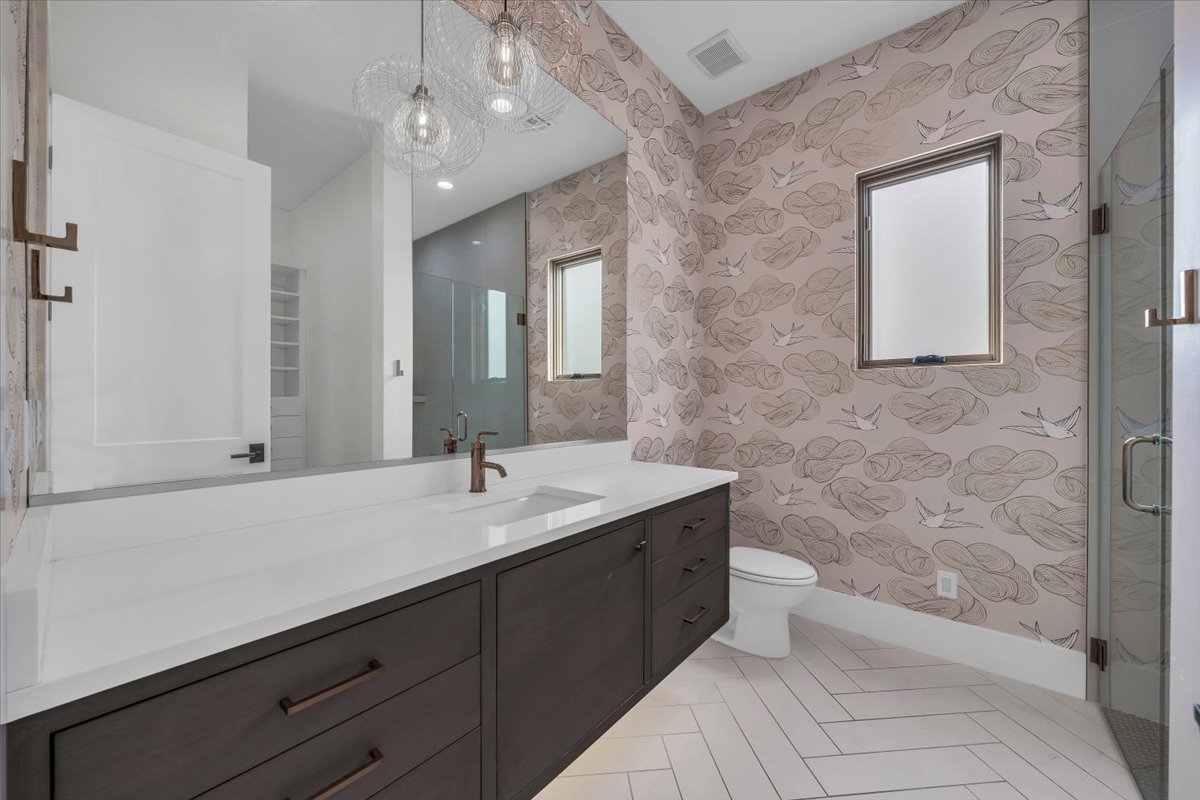 Full bath featuring wallpapered walls, vanity, a shower stall, and light tile patterned floors