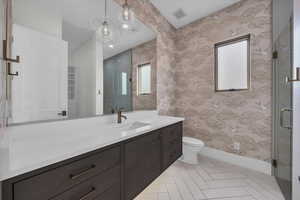 Full bath featuring wallpapered walls, vanity, a shower stall, and light tile patterned floors