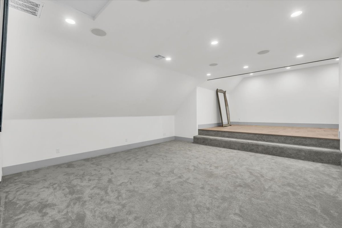 Additional living space with light carpet, vaulted ceiling, and recessed lighting