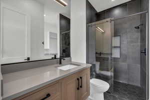 Full bath with vanity, a shower stall, and dark tile patterned flooring