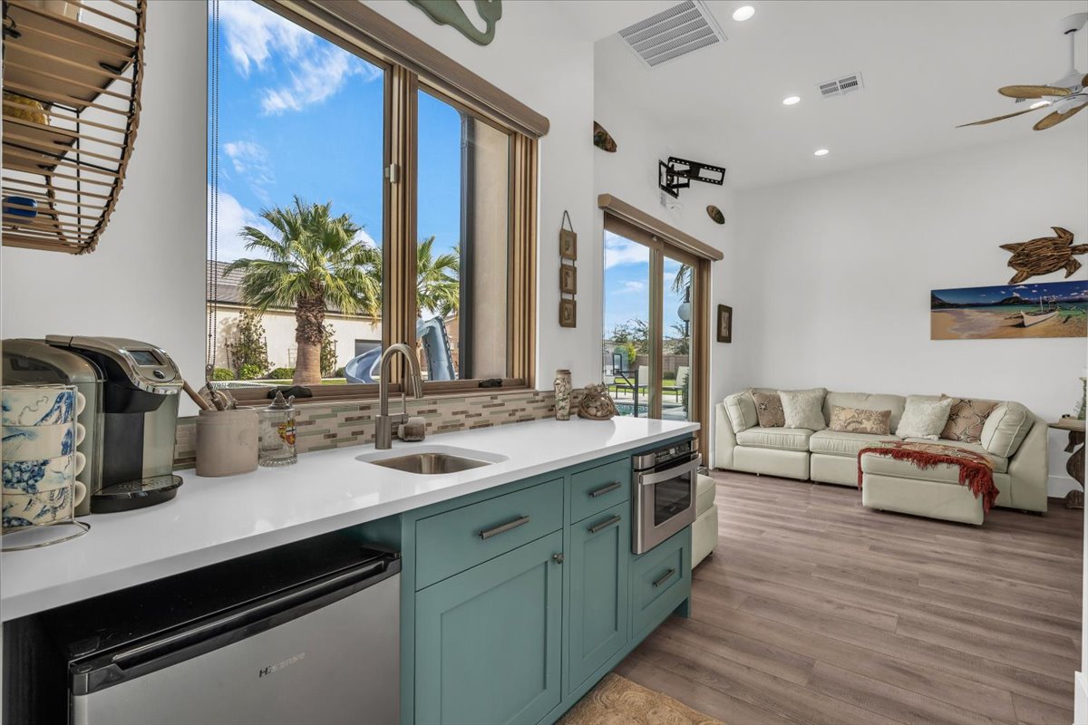 Kitchen with stainless steel appliances, open floor plan, light stone counters, green cabinets, and recessed lighting