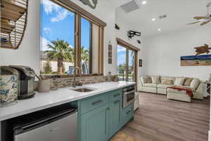 Kitchen with stainless steel appliances, open floor plan, light stone counters, green cabinets, and recessed lighting