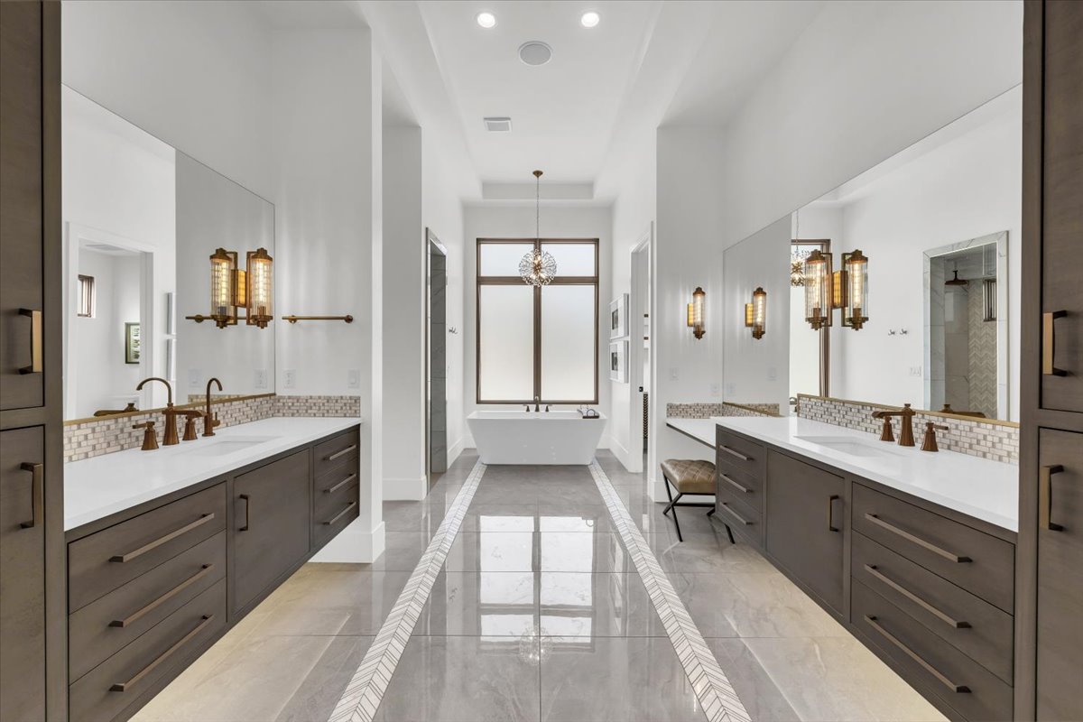 Bathroom featuring two vanities, decorative backsplash, hanging lights, and a soaking tub