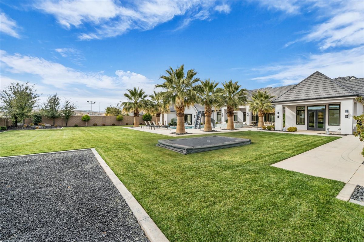 Back of house with a patio, a lawn, and stucco siding