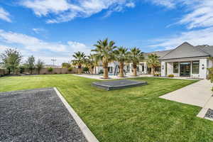 Back of house with a patio, a lawn, and stucco siding