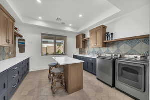 Laundry area featuring a raised ceiling, recessed lighting, washing machine and dryer, cabinet space, and light tile patterned floors