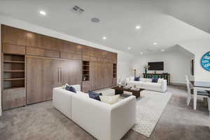 Living room featuring light colored carpet, recessed lighting, built in shelves, and vaulted ceiling