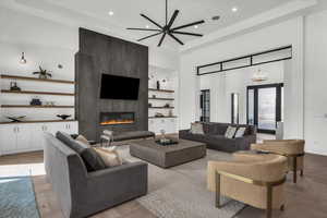 Living room featuring a ceiling fan, parquet floors, a fireplace, hanging lights, and a high ceiling
