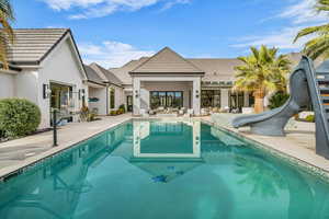 Swimming pool with a water slide and a patio area