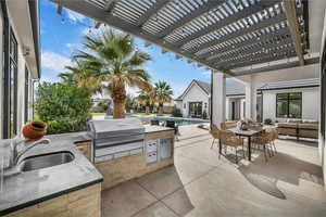 View of patio with an outdoor kitchen, a pergola, an outdoor pool, and outdoor lounge area