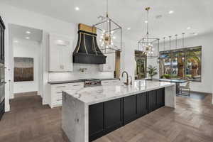 Kitchen featuring dark stone countertops, parquet floors, a large island, two tone cabinets, and suspended lighting