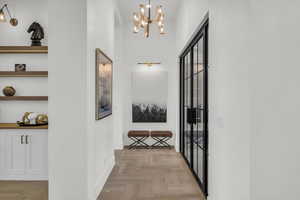Hallway with parquet flooring and a chandelier