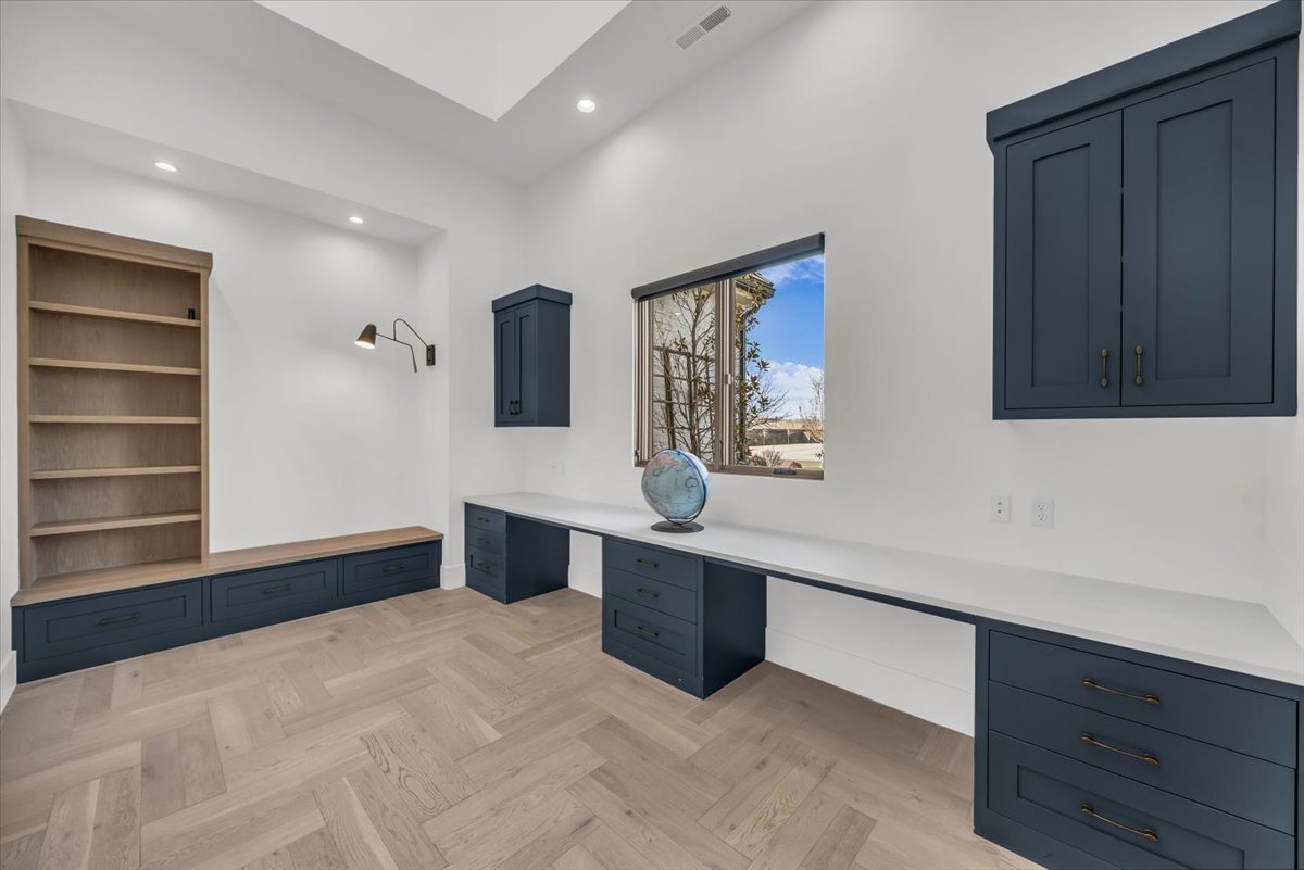 Unfurnished office with built in desk, parquet flooring, and recessed lighting