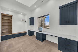 Unfurnished office with built in desk, parquet flooring, and recessed lighting