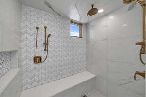 Bathroom featuring tiled shower and tile walls
