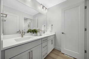Full bathroom with double vanity and light wood-style floors