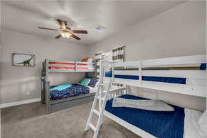 Bedroom featuring carpet floors, ceiling fan, and a textured ceiling