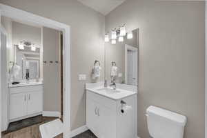 Full bathroom featuring two vanities and dark wood-style floors