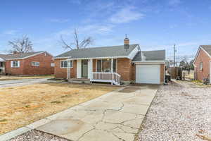 Ranch-style house with a shingled roof, concrete driveway, brick siding, an attached garage, and a chimney