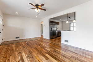 Unfurnished living room featuring dark wood-style floors, ceiling fan, and recessed lighting