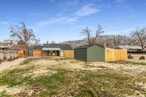 Back of house with a patio area, a fenced backyard, a chimney, a storage shed, and a mountain view