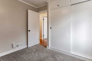 Unfurnished bedroom featuring crown molding, carpet, and a closet