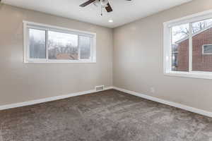 Carpeted spare room featuring ceiling fan and healthy amount of natural light