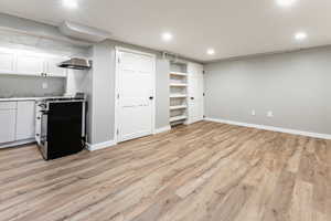 Finished below grade area featuring light wood-type flooring and recessed lighting