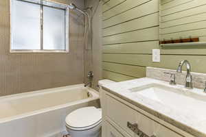 Bathroom with vanity, shower / bathtub combination, and wooden walls