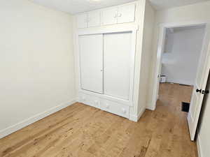 Unfurnished bedroom featuring light wood-type flooring, a textured ceiling, and a closet