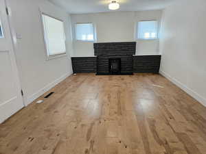 Unfurnished living room with light wood-style floors and a stone fireplace