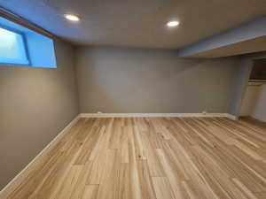 Basement with light wood-style flooring, recessed lighting, and a textured ceiling
